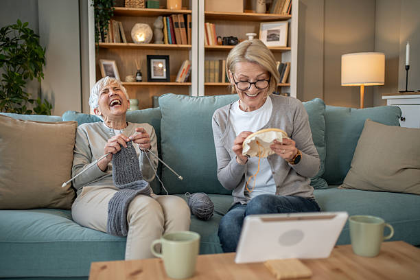 istock Two senior women laughing while knitting and embroidering at home 2208181278