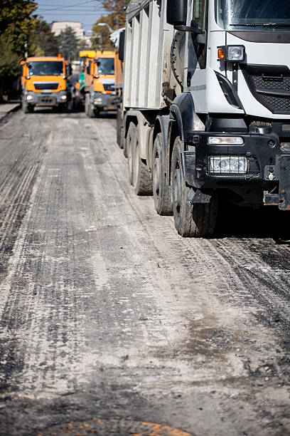 istock Construction trucks working on a road improvement project in a bustling urban area 2208183418