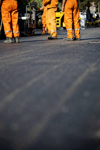 istock Workers in bright orange uniforms repairing a road during the day 2208184053