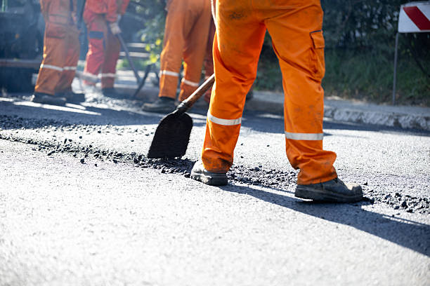 istock Workers repair and resurface a roadway in bright orange uniforms during daylight hours 2208184085