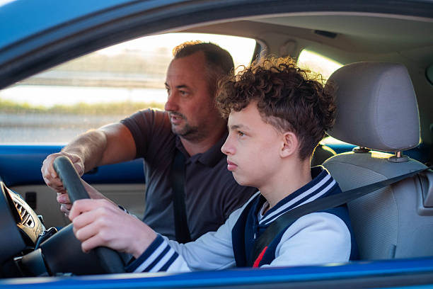 istock a teenager learns to drive a car with an instructor helping him 2208188893
