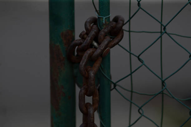 istock Rusty Chains Hanging on a Green Fence Gate with a Striking Background 2208194048