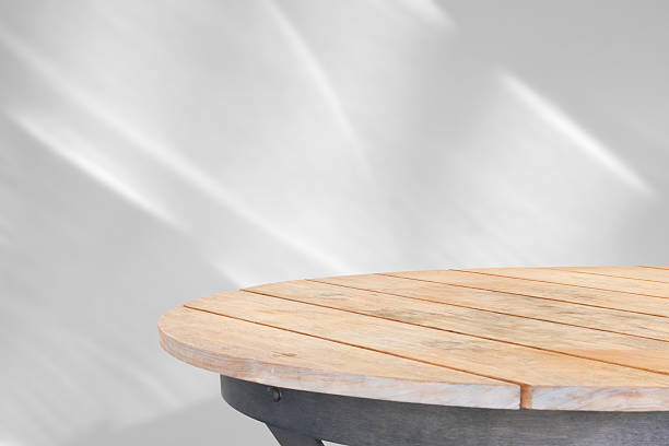 Round wood table top with abstract shadow drop on white wall background for mockup product display