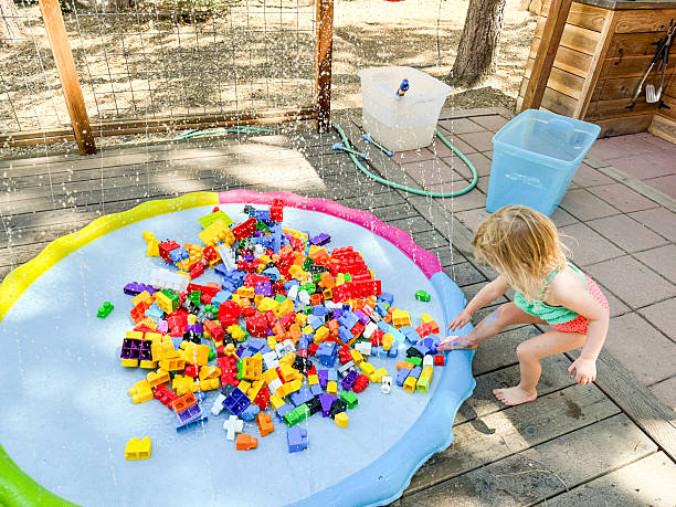 Toddler playing with blocks on a splash pad in summer