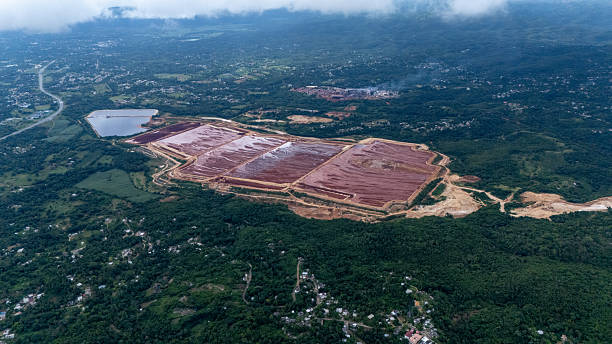 Aerial view of the Alpart Bauxite Mine, one of the largest bauxite mining operations in Jamaica. The image showcases the extensive mining site, with large open pits and processing areas surrounded by the island's lush landscape.