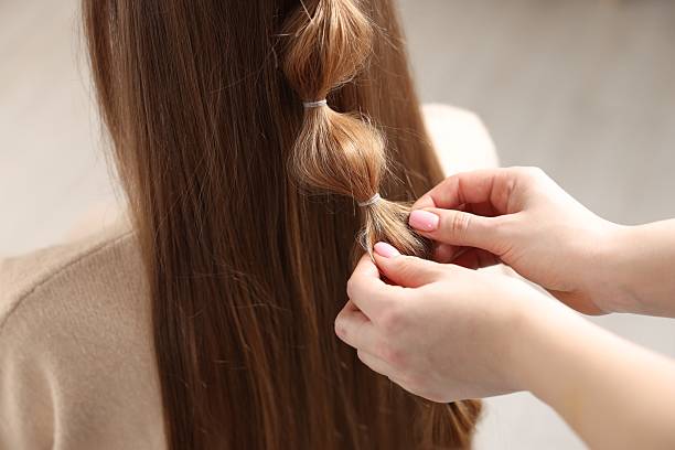 istock Professional stylist braiding woman's hair on blurred background, closeup 2208206100