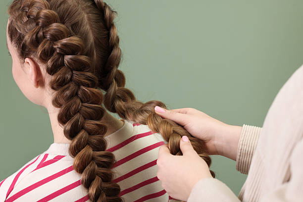 istock Professional stylist braiding woman's hair on olive background, closeup 2208206143