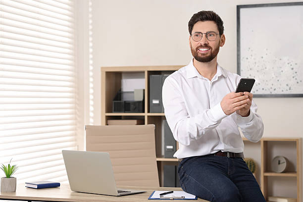 istock Smiling man with smartphone in office. Space for text 2208209000