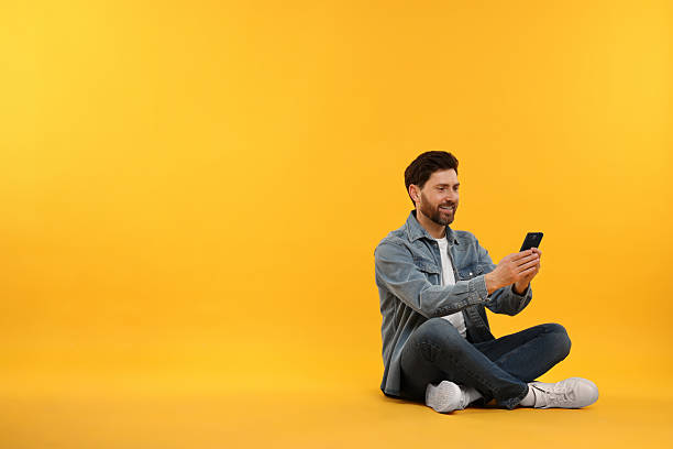 istock Happy man with smartphone on yellow background. Space for text 2208209213