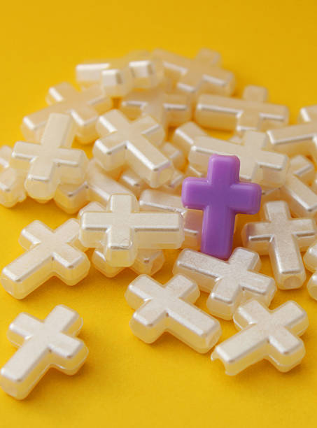 istock Purple cross on a group of pearly white crosses - vertical format 2208209216