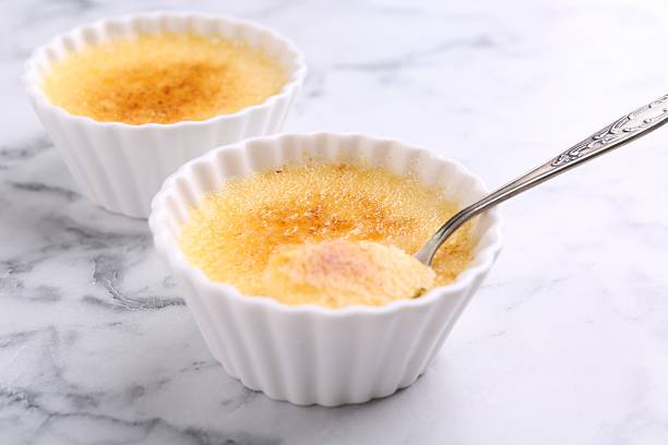 istock Delicious creme brulee in bowls and spoon on white marble table, closeup 2208213839