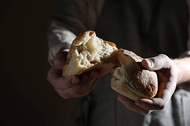 istock Man breaking loaf of fresh bread on dark background, closeup 2208214705