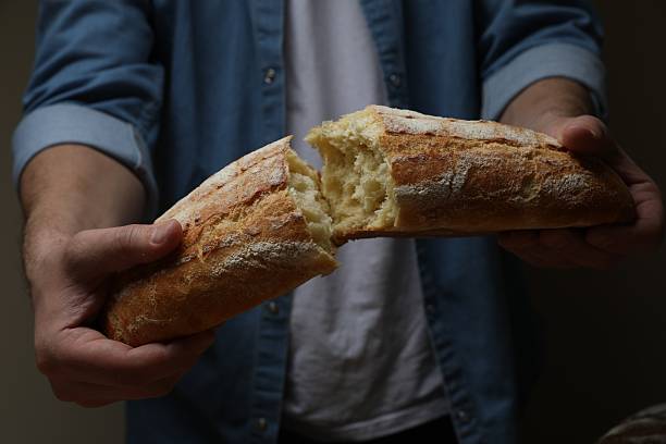 istock Man breaking loaf of fresh bread on dark background, closeup 2208214893