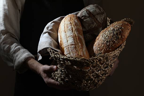 istock Man holding wicker basket with different types of bread on dark brown background, closeup 2208214983