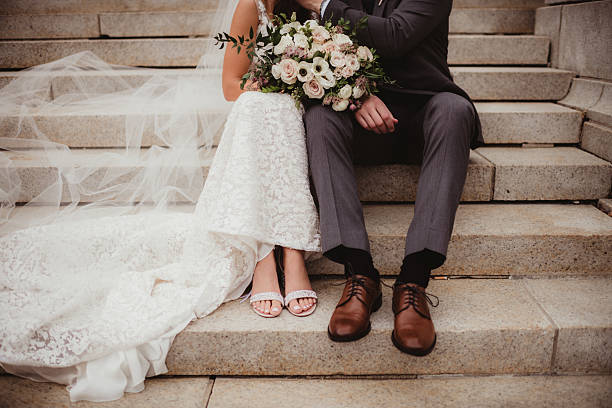 istock Bride and groom sitting on steps with bouquet 2208219242