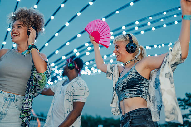 istock Friends listening music and dancing at silent disco party under string lights 2208219485