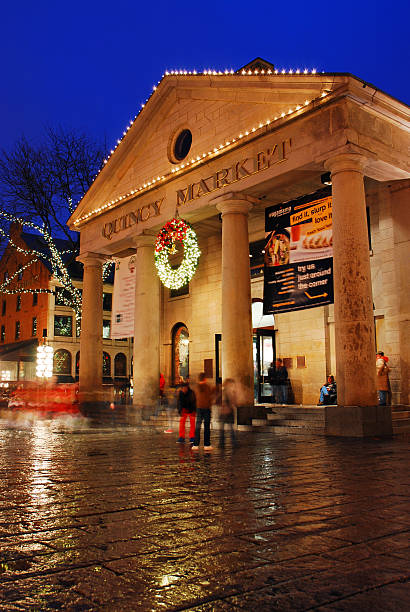 Boston, MA, USA December 4, A large illuminated Christmas wreath hangs over the entrance to the historic Quincy Market at night in Boston