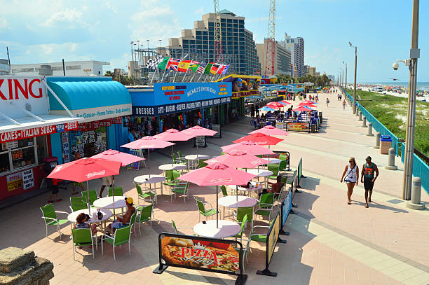 Daytona Beach, FL, USA July 12 A young couple walks on the boardwalk in Daytona Beach, Florida, passing cafes and alfresco dining with umbrellas