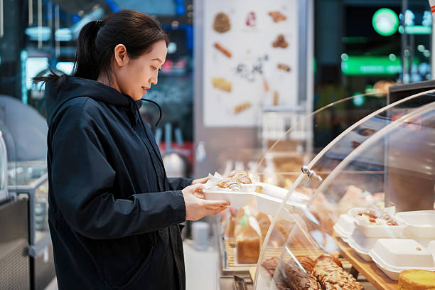 istock Woman Selecting Pastries in Modern Bakery Display 2208229774