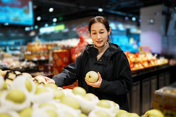 istock Woman Choosing Fresh Apples in Modern Grocery Store 2208233366