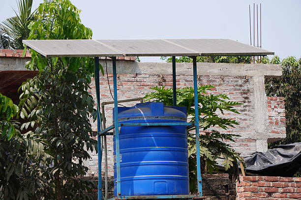 A blue water tank with a solar panel roof structure beside a newly constructed building