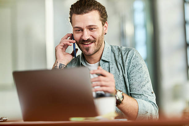 istock Happy freelancer talking on cell phone while working on laptop in the office. 2208244987