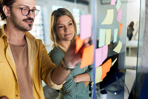 istock Creative colleagues making mind map on a glass wall in the office. 2208245648