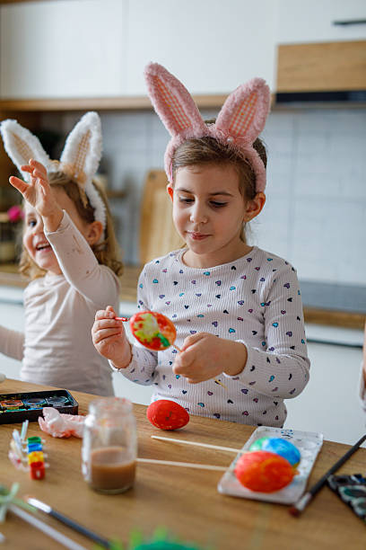istock Two cute girls painting eggs for Easter holiday in kitchen 2208248857