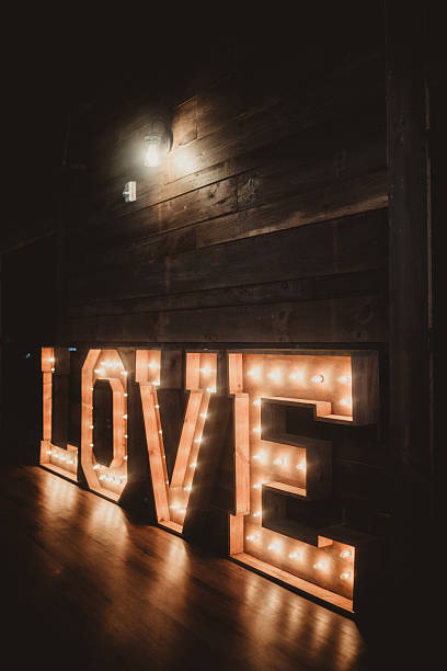 Illuminated light up love sign at rustic wedding reception in barn