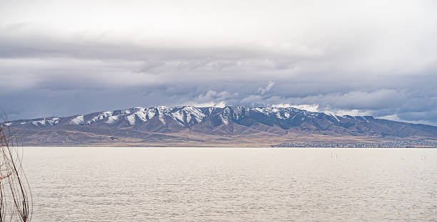 istock A snow capped mountain range stretching across the horizon behind a calm lake under a cloudy sky, creating a peaceful and expansive natural scene in utah county 2208250646