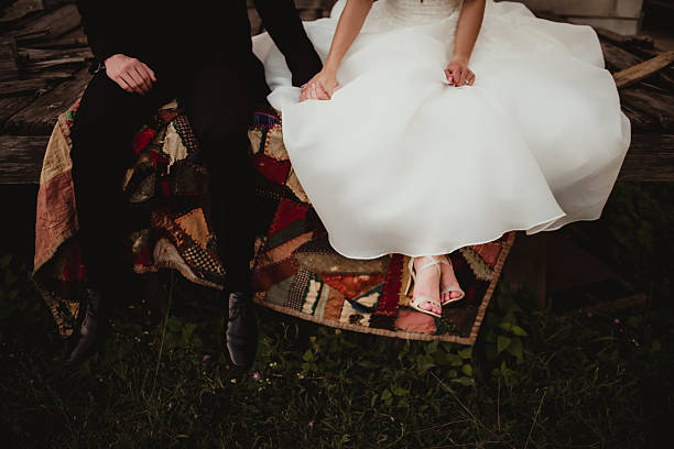 Bride and groom sitting together outdoors on vintage quilt on their wedding day