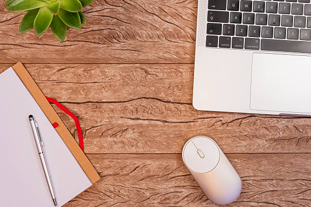 istock Wooden desktop featuring laptop, notepad, pen, mouse, and green succulent, professional home office workspace arrangement 2208252175
