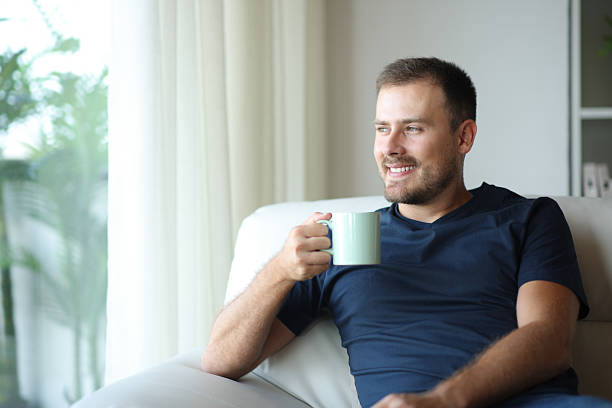 istock Happy man at home drinking coffee or tea looking through a window 2208261452