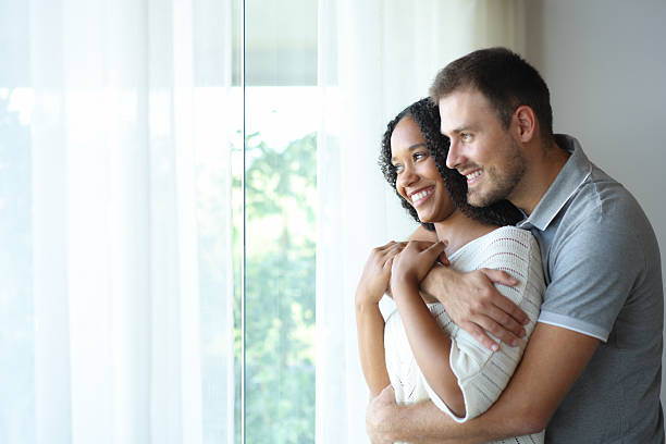 istock Happy interracial couple hugging looking away at home 2208261589