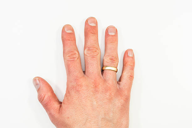 A hand wearing a wedding ring is laid flat on a plain white background, illustrating ideas of relationship, identity, biometric scanning or emotional symbolism