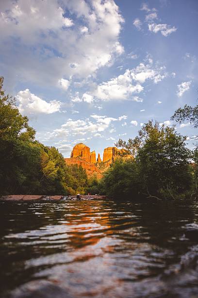 Scenic view of Cathedral Rock in Sedona, Arizona, with a river in the foreground and a vibrant sky above.