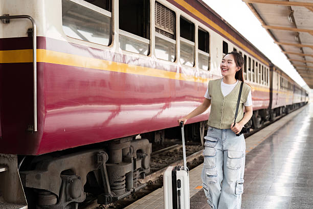 istock Traveling and Experiences. A young woman with a suitcase smiling as she walks alongside a train. 2208267979