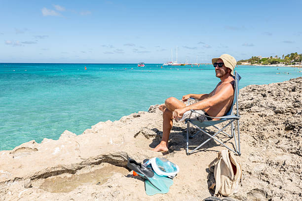 istock Man Relaxing on Rocky Beach with Crystal Blue Ocean View 2208269838