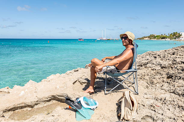 istock Man Relaxing on Rocky Beach with Crystal Blue Ocean View 2208269839