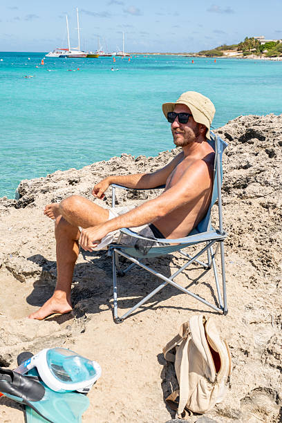 istock Man Relaxing on Rocky Beach with Crystal Blue Ocean View 2208269848