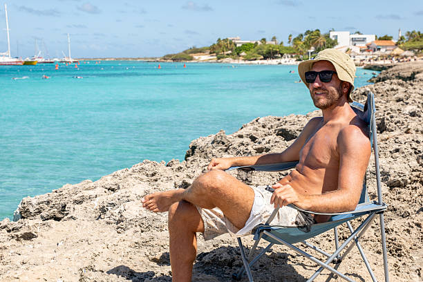 istock Man Relaxing on Rocky Beach with Crystal Blue Ocean View 2208269851