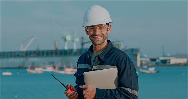 Portrait maintenance engineer smiling handhold computer notebook after meeting plan to repair or rebuild a large bulk ship damaged at a Commercial Shipyard.