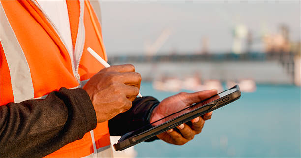 Young engineers using digital tablets and note reports to plan to repair or rebuild a large bulk ship damaged at a Commercial Shipyard.