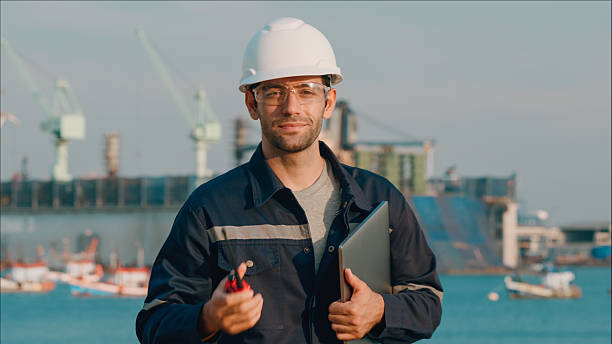 istock Portrait maintenance engineer smiling handhold computer notebook after meeting plan to repair or rebuild a large bulk ship damaged at a Commercial Shipyard. 2208274555