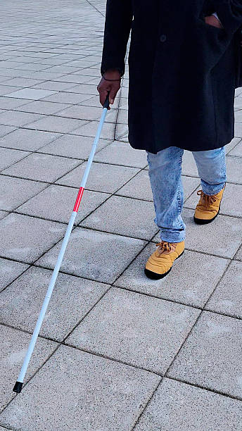 istock Low section of a visually impaired person walking on a sidewalk using a white cane 2208275543