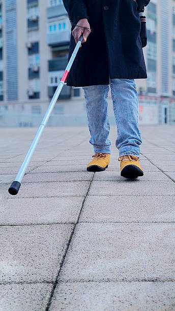 istock Close up of a visually impaired person walking on a sidewalk using a white cane 2208275555