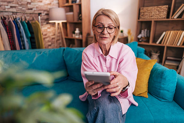 istock Senior woman using digital tablet on sofa at home 2208277300