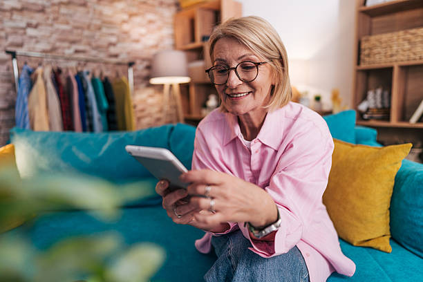istock Smiling senior woman using digital tablet at home 2208277304