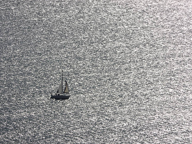 Yacht in full sail in an expanse of sea in bright sunshine