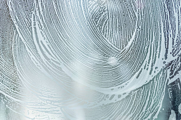 soap foam pattern wipe marks on window glass, window cleaning , blue background. High quality photo
